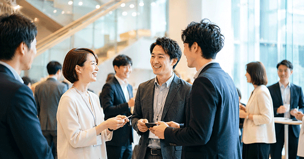 ビジネス交流会で笑顔で名刺交換をしている参加者たちの様子